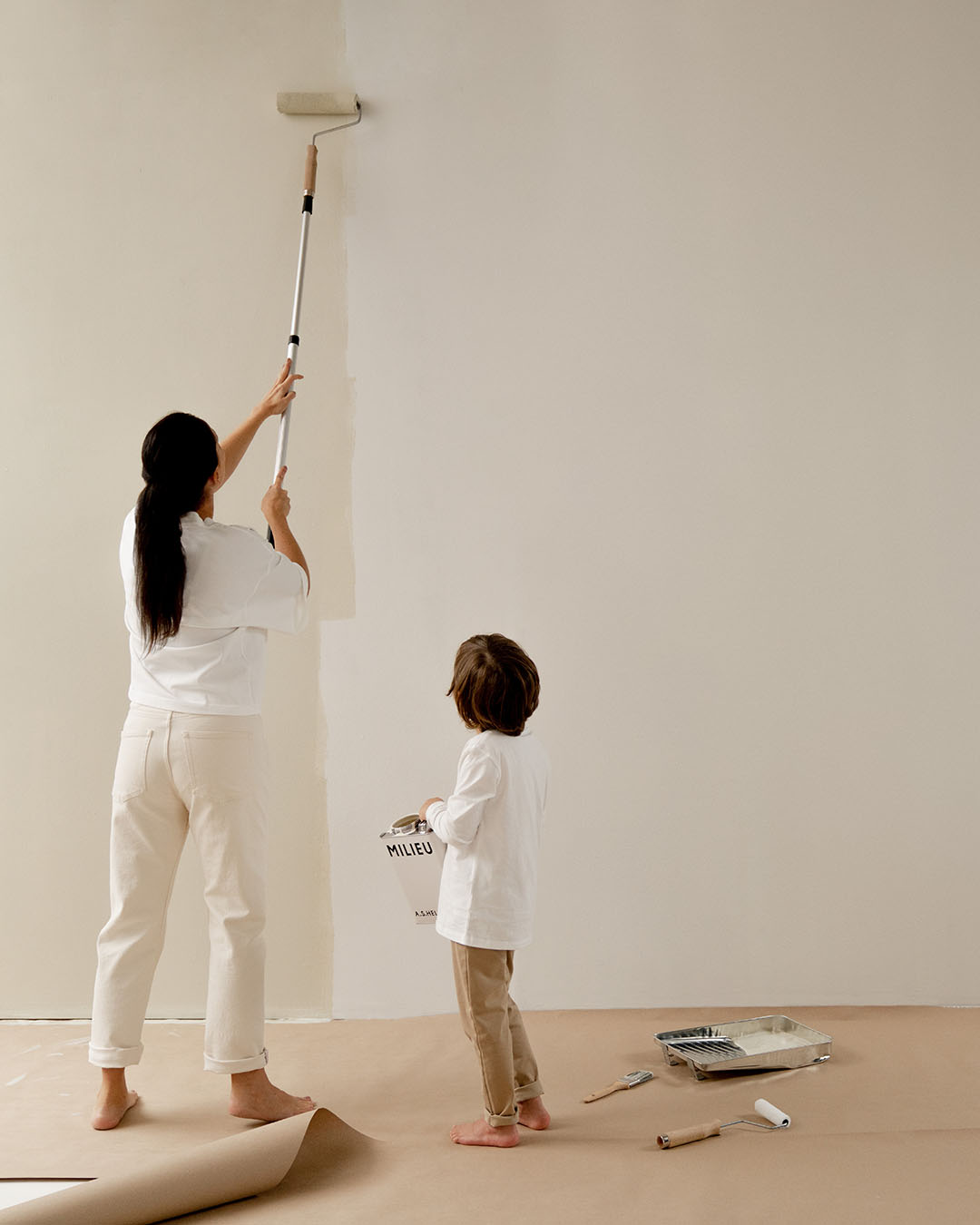 Painter using a roller on a bright interior wall